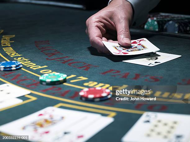 male croupier holding card at blackjack table, close-up - casino stock-fotos und bilder