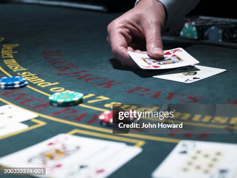 Male croupier holding card at Blackjack table, close-up Male croupier holding card at Blackjack table, close-up