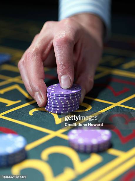 man placing stack of chips on number at roulette table, close-up - casino worker ストックフォトと画像