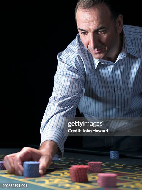 man placing chips on number at roulette table, close-up - roulette stockfoto's en -beelden