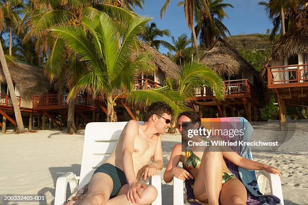 cook islands, aitutaki, couple sunbathing, smiling at each other - aitutaki stock pictures, royalty-free photos & images