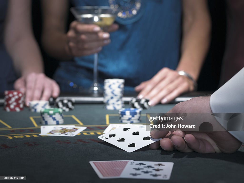 Two women playing Blackjack, croupier turning over card, close-up
