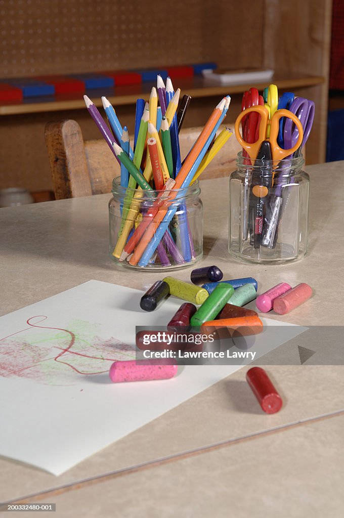 Assortment of coloured crayons, pencils and scissors on table