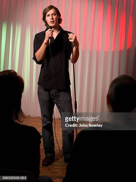 young male stand-up comedian performing on stage, portrait - comedian mic stock pictures, royalty-free photos & images