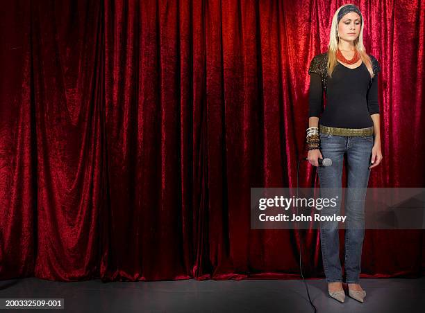 young woman standing on stage, holding microphone, looking down - 怯場 個照片及圖片檔