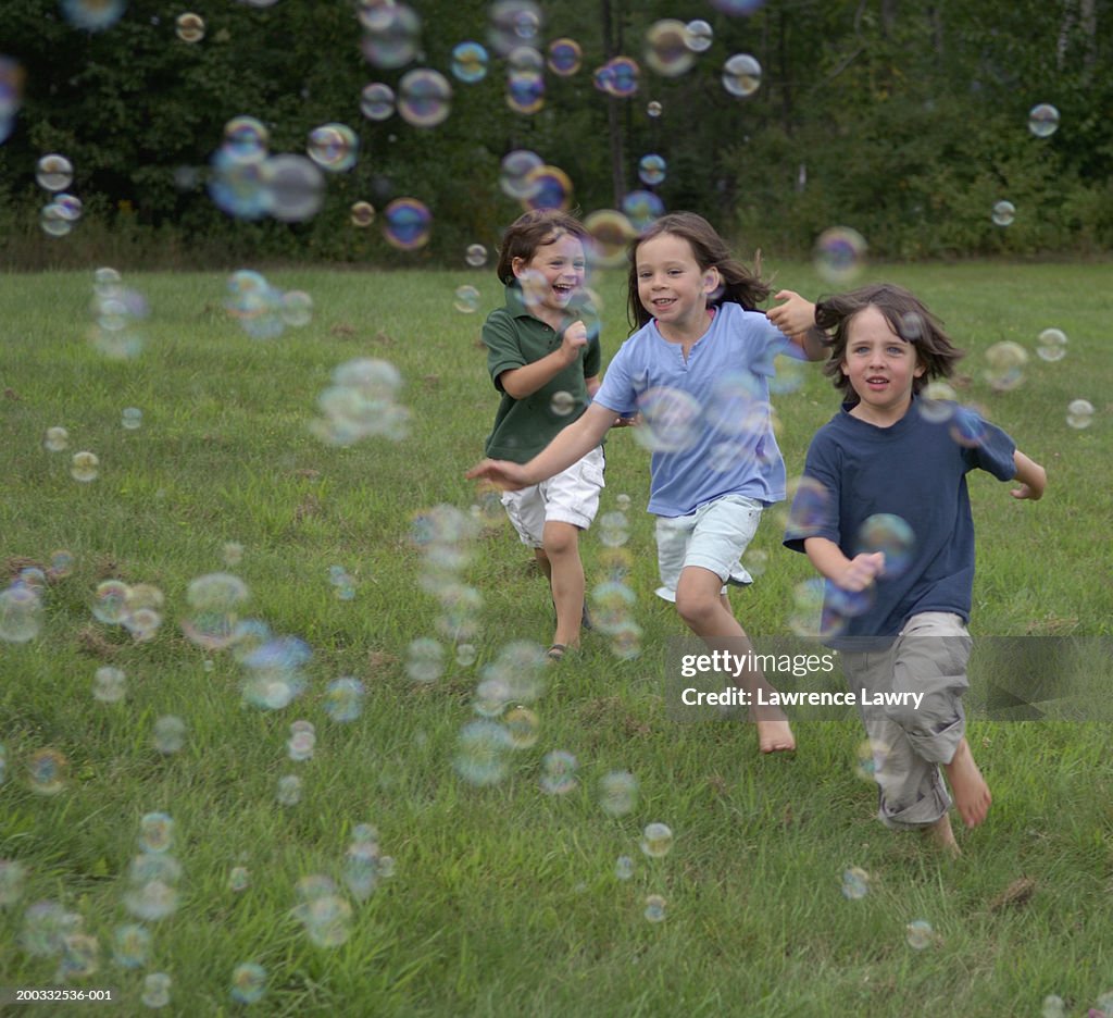 Three Children Chasing Bubbles Smiling High-Res Stock Photo - Getty Images