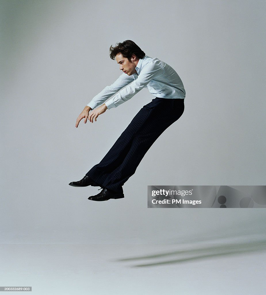 Young businessman flying backwards, side view