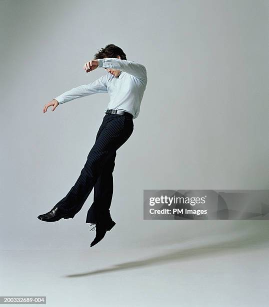 young businessman flying backwards, side view - in der luft schwebend stock-fotos und bilder