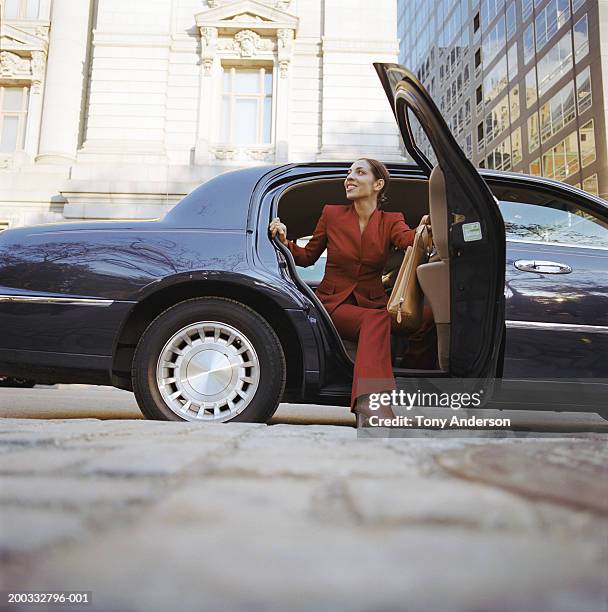 businesswoman exiting car, smiling - businesswoman nyc stockfoto's en -beelden