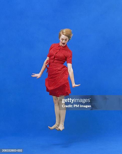 young woman levitating with  surprise look on face - looking down photos et images de collection