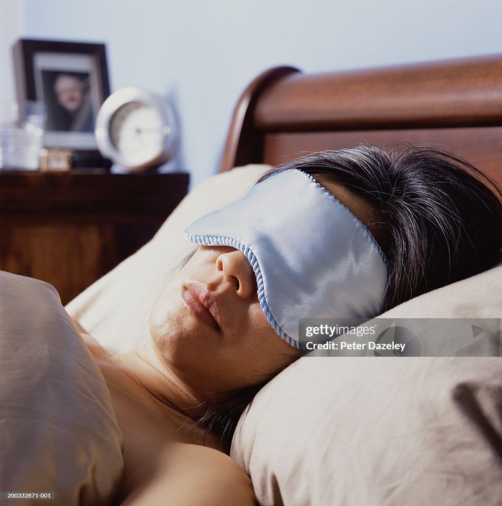 Mature woman sleeping in bed, wearing eye mask, close-up