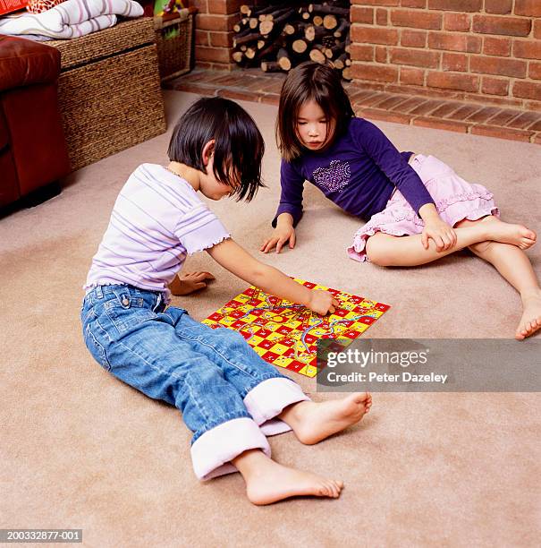 two girls (4-6) on floor playing snakes and ladders, elevated view - snakes and ladders stock pictures, royalty-free photos & images