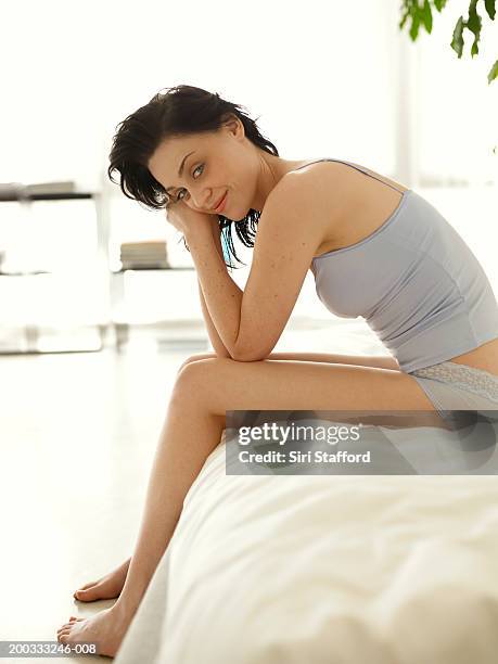 young woman sitting on bed, smiling - cami - fotografias e filmes do acervo