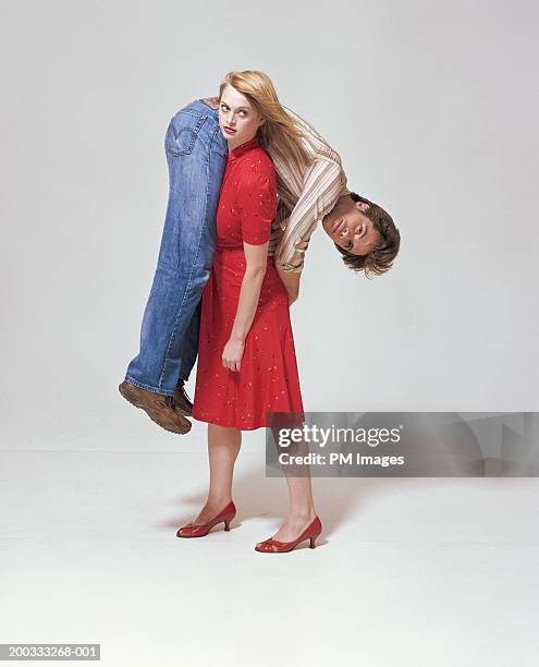 woman carrying man on shoulder - red shirt stockfoto's en -beelden