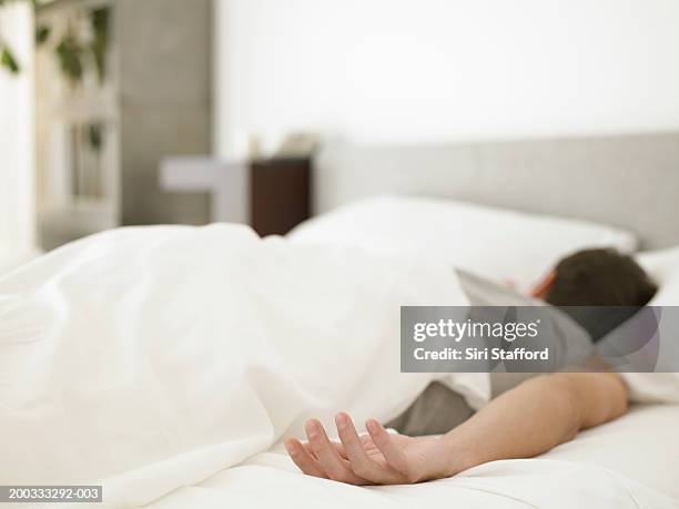 man lying on bed (focus on hand) - lying on front stock pictures, royalty-free photos & images