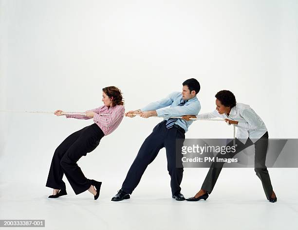 two businesswomen and businessman pulling rope, side view - 綱引き ストックフォトと画像