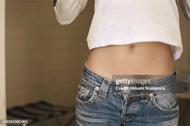 young woman exposing stomach, mid section - menschlicher bauch stock-fotos und bilder