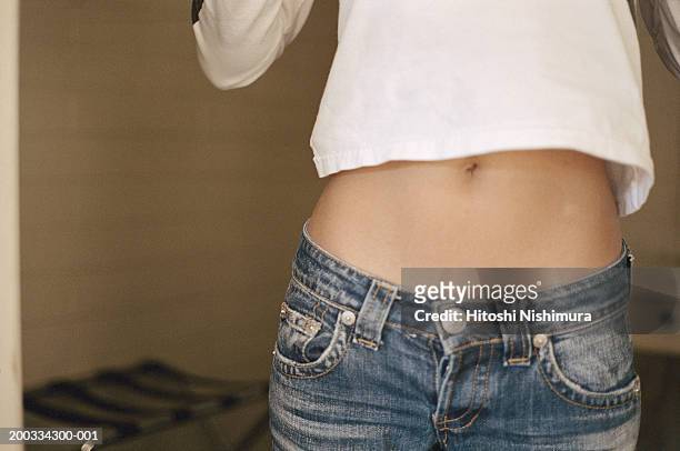 young woman exposing stomach, mid section - stomach stock pictures, royalty-free photos & images