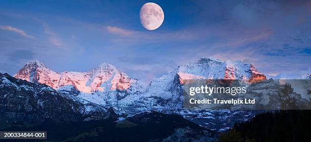 switzerland, berner oberland, moon over mountains, dusk - eiger mönch jungfrau stockfoto's en -beelden