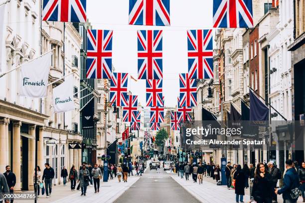 crowds of people on luxury shopping new bond street decorated with british flags, london, uk - bond street stock-fotos und bilder