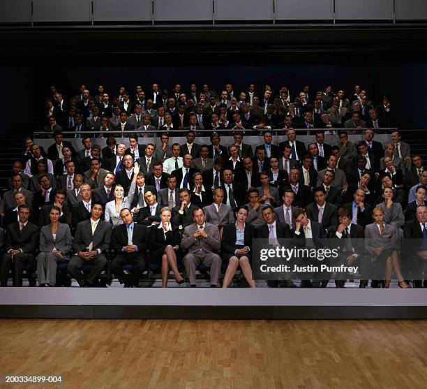 spotlight on woman in auditorium raising arm (digital composite) - auditorium seats stock pictures, royalty-free photos & images