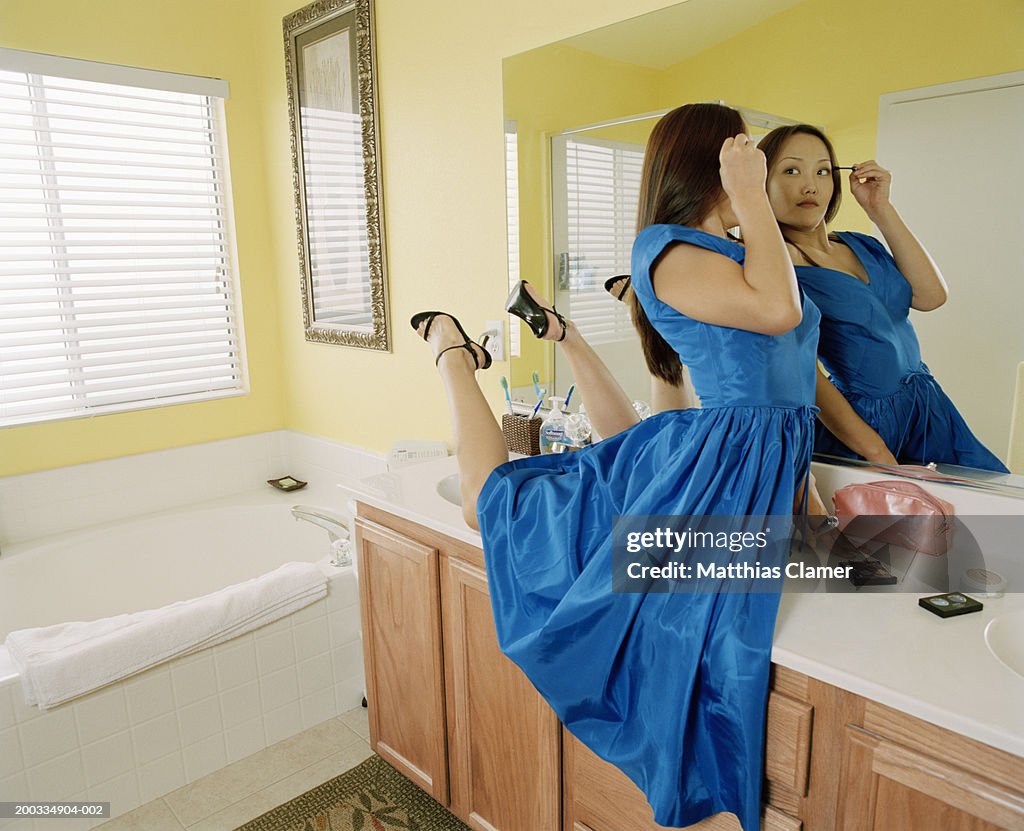 Young female contortionist applying make-up in bathroom, side view