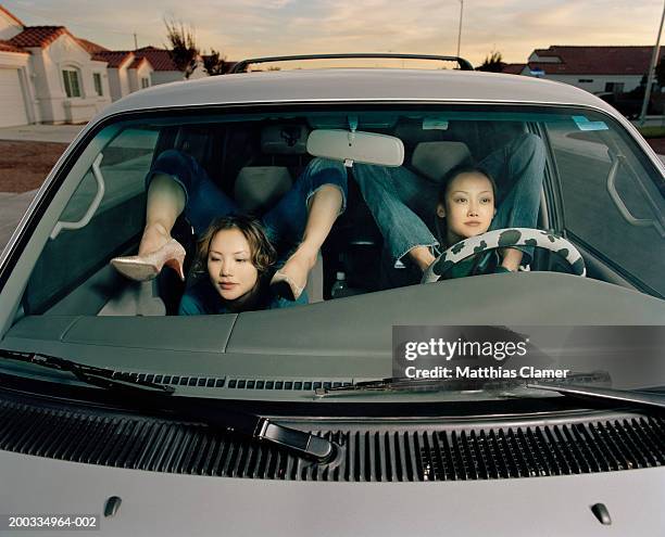 young female contortionists in car bending legs over shoulders - young contortionist stockfoto's en -beelden