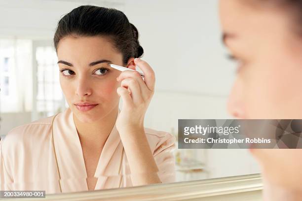 young woman plucking eyebrows, close-up, reflection in mirror - eyebrow stock-fotos und bilder