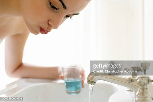 young woman rinsing mouth, leaning over sink, close-up - mouthwash stock-fotos und bilder