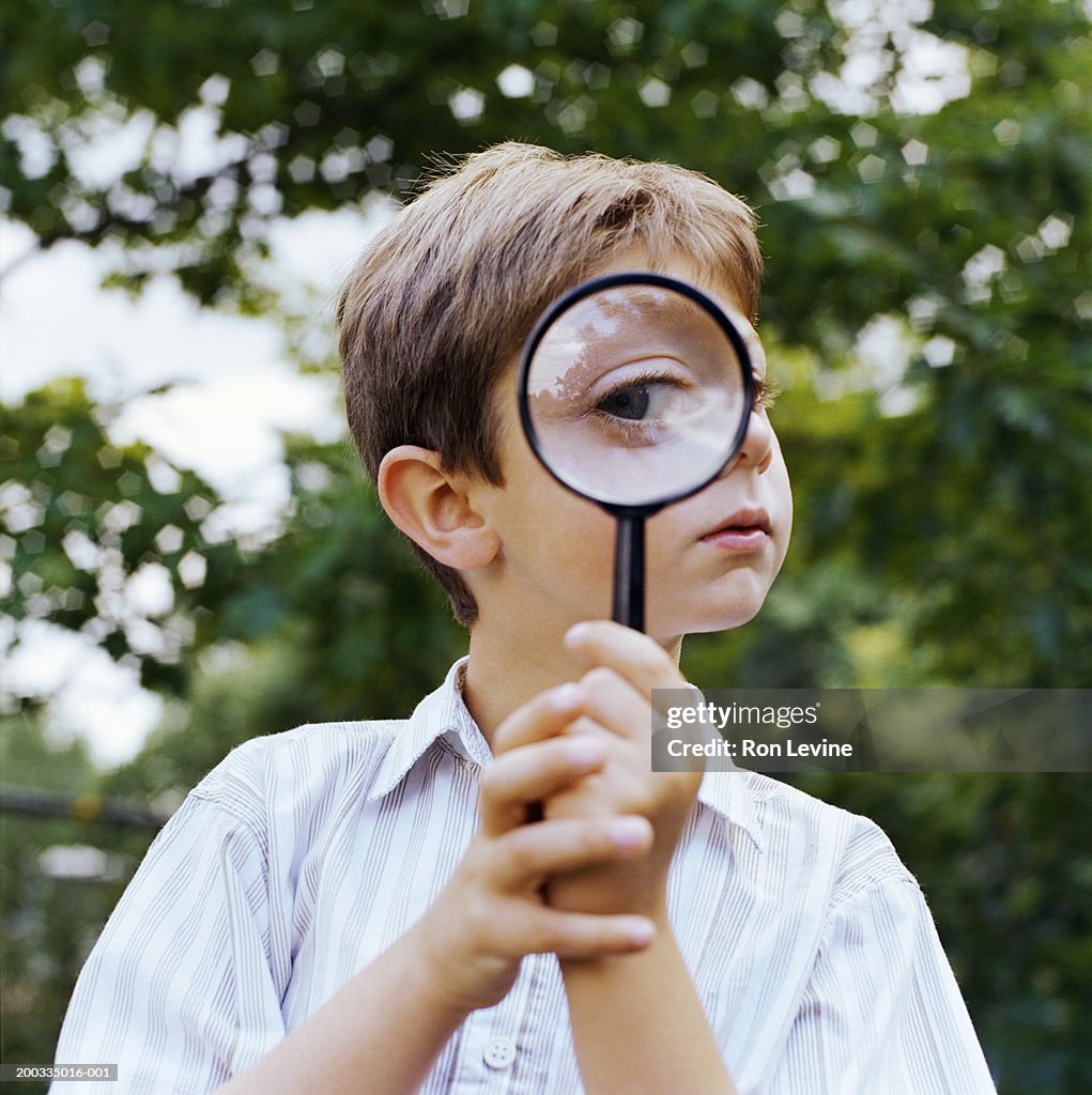Boy (5-7) looking through magnifying glass