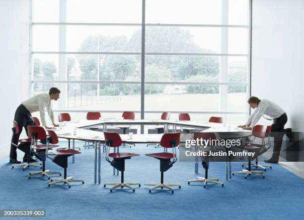 two businessmen looking at each other over round table in meeting room - round table stock pictures, royalty-free photos & images