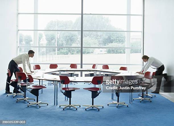 two businessmen looking at each other over round table in meeting room - round table imagens e fotografias de stock