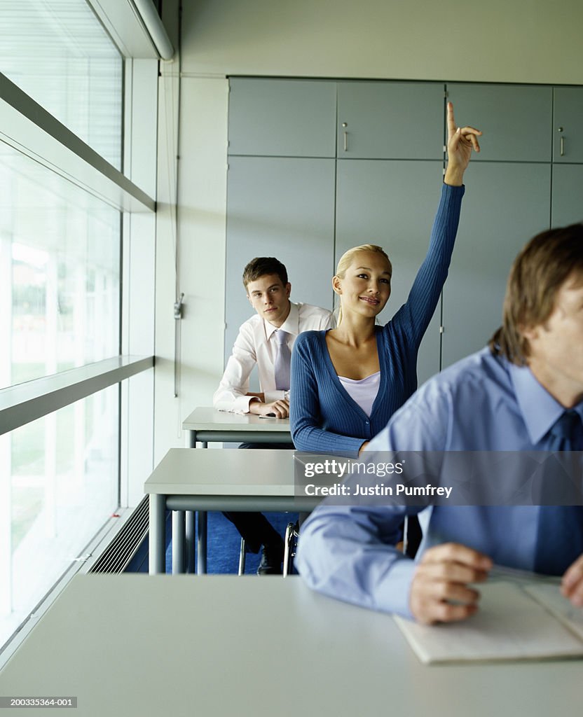 Woman raising hand in classroom, smiling