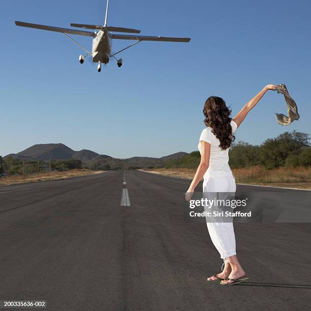 young woman waving scarf to private plane in flight - plane taking off stock-fotos und bilder