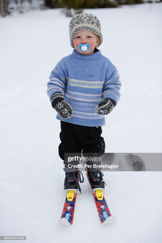 Boy (2-4) on skis with pacifier in mouth, portrait