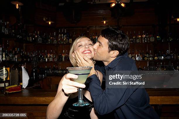 couple in bar, man kissing woman's cheek - cheek stock pictures, royalty-free photos & images