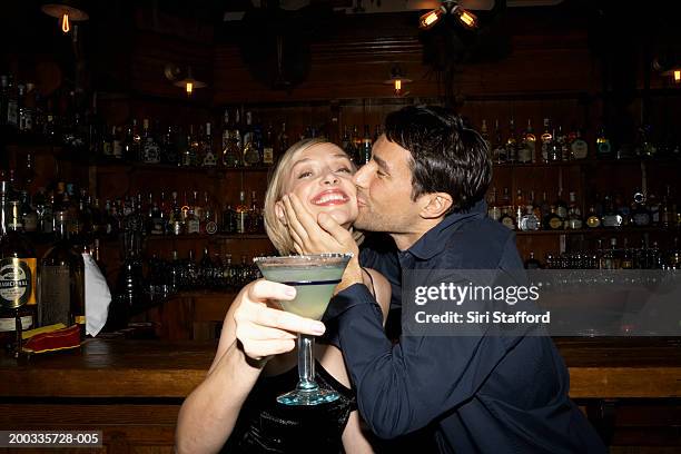 couple in bar, man kissing woman's cheek - cheek kiss stock pictures, royalty-free photos & images