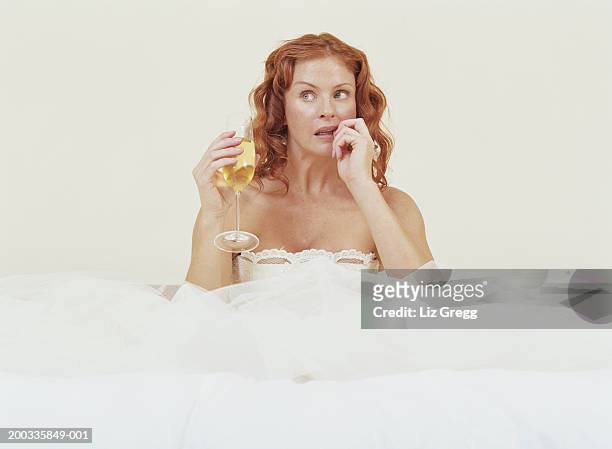 bride sitting amongst netting of dress, holding glass of champagne - white wedding dress stock pictures, royalty-free photos & images