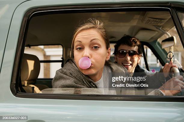 couple in car, woman blowing bubble, portrait - side by side stock-fotos und bilder