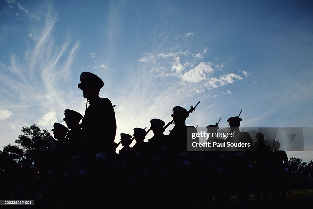 Silhouetted naval cadets marching in formation, low angle view