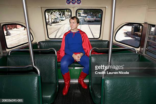 man in superhero costume riding bus, hands clasped - dress up stock pictures, royalty-free photos & images