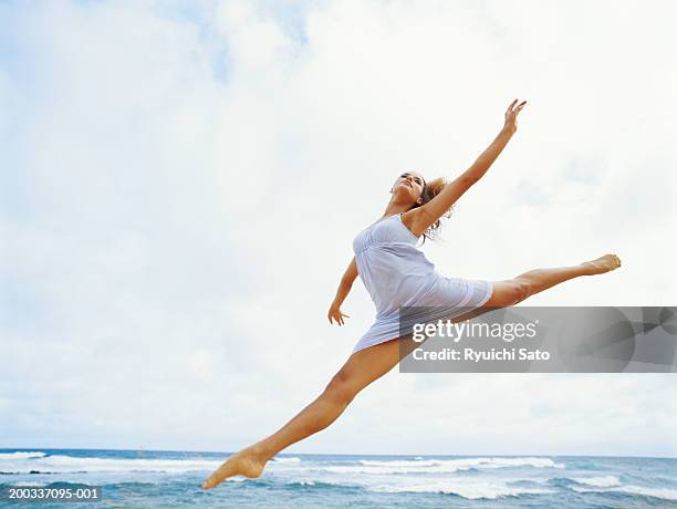 young woman jumping on beach, low angle view - blonde long legs 個照片及圖片檔