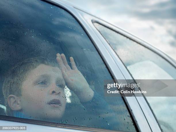 boy (6-8) looking out of car window, view through glass - winter car window stock-fotos und bilder