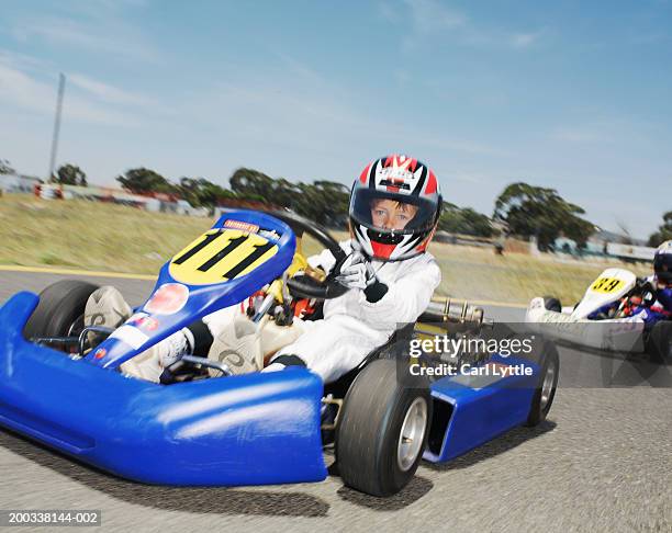 boy (9-11) driving go-cart on race track, portrait (blurred motion) - helmet cart foto e immagini stock