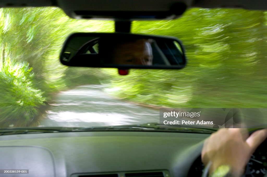 Man driving car, rear view, close-up of hand (blurred motion)