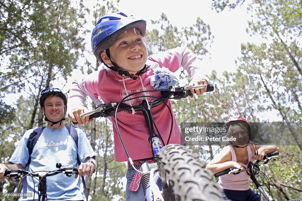 Family of cyclists in forest, smiling, low angle view