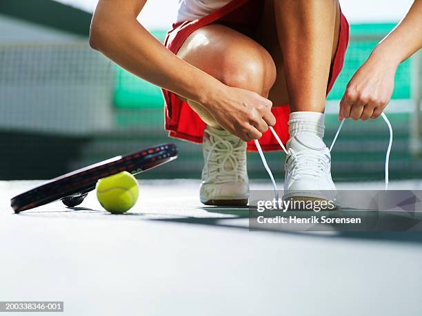 young woman crouching on tennis court, tying laces, ground view - desamarrado imagens e fotografias de stock