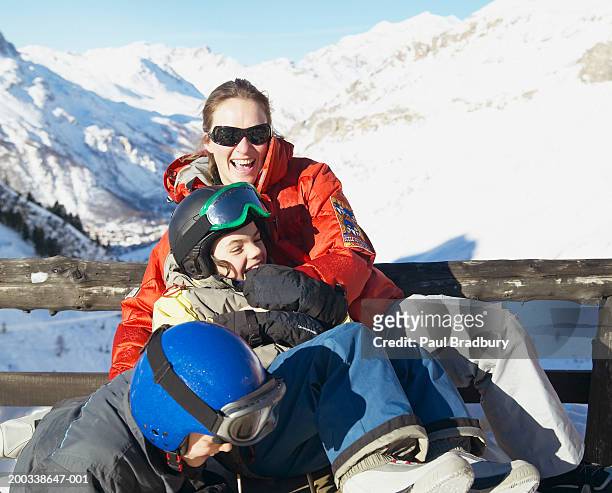 woman with son and daughter (8-10) relaxing at ski resort, laughing - val d'isere stock pictures, royalty-free photos & images