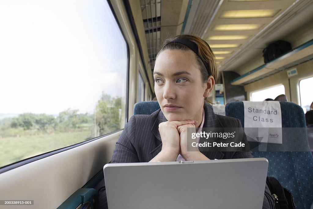 Woman by laptop looking out train window