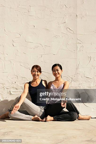 two young women in matsyendrasana pose, portrait - ardha matsyendrasana stock-fotos und bilder